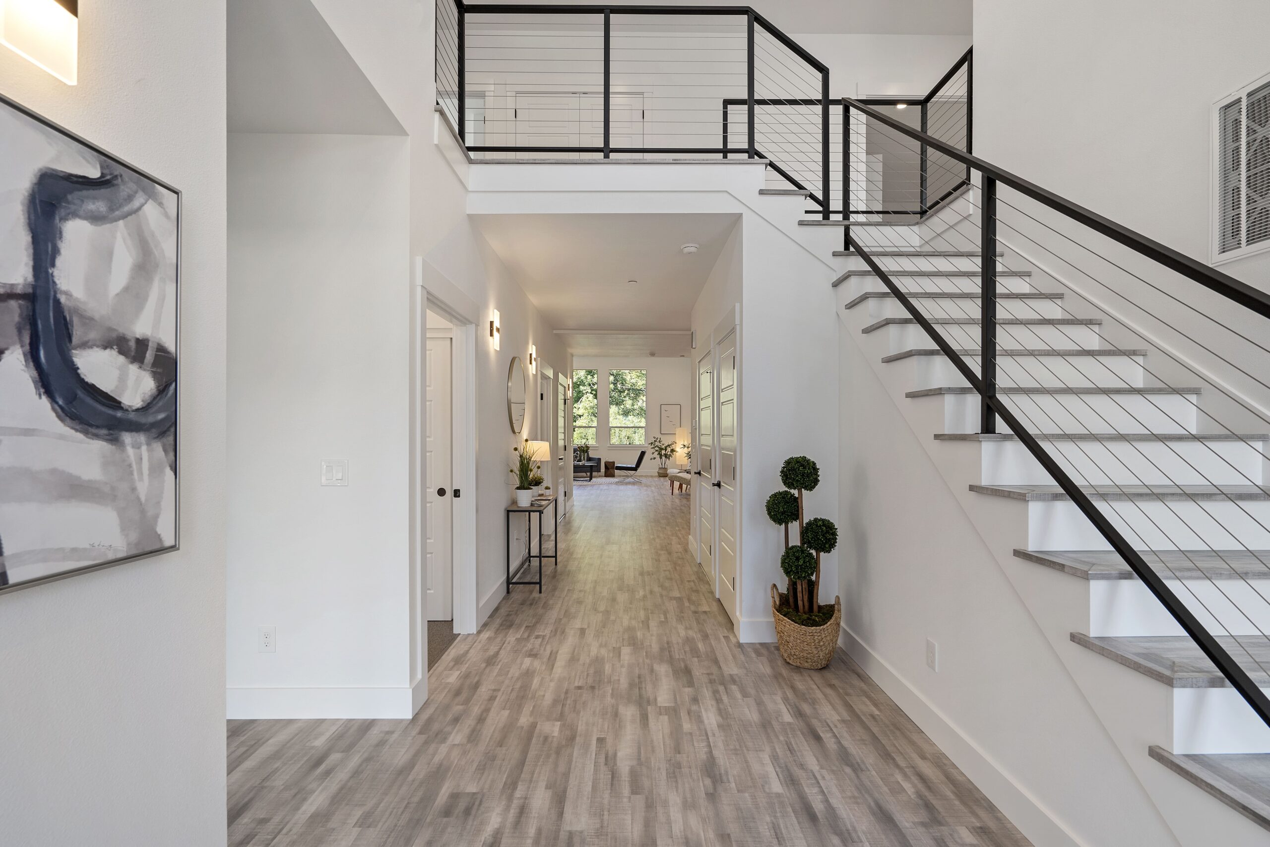 Modern two-story home with large windows and a landscaped front yard under a blue sky.