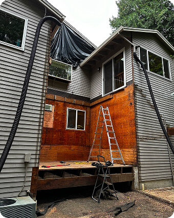 Construction workers framing a wooden house under a clear blue sky